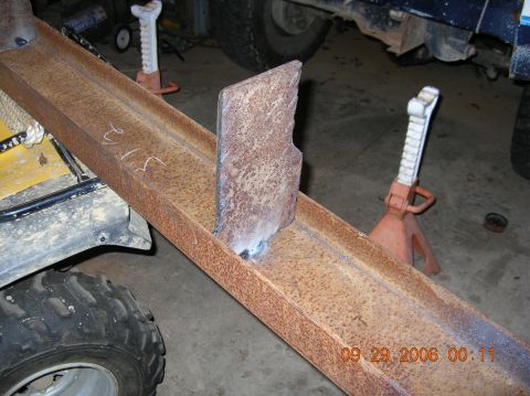 1991 Ford F-150 - A close-up view of a rusted metal frame with a welded plate, supported by jack stands.