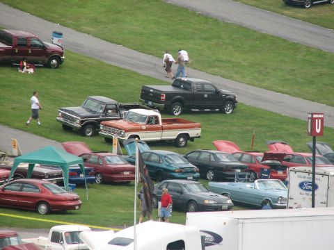 1992 Ford Bronco - A variety of vehicles are displayed on a grassy area, with attendees observing them.