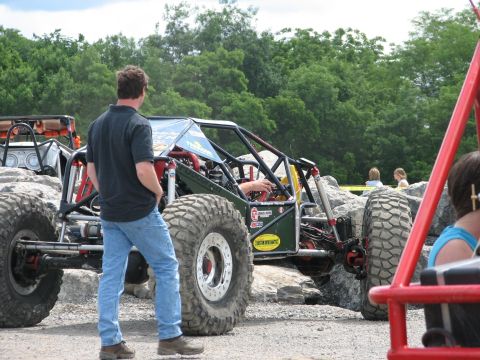 1992 Ford Bronco - A man stands beside a custom off-road buggy during an event.