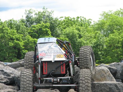 1992 Ford Bronco - Custom off-road buggy with large tires navigates a rocky obstacle course. Decals include 'FASTECH' and 'KC'.
