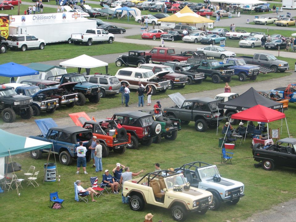 Aerial view of Bronco and Ford truck show field with rows of trucks, canopies and spectators