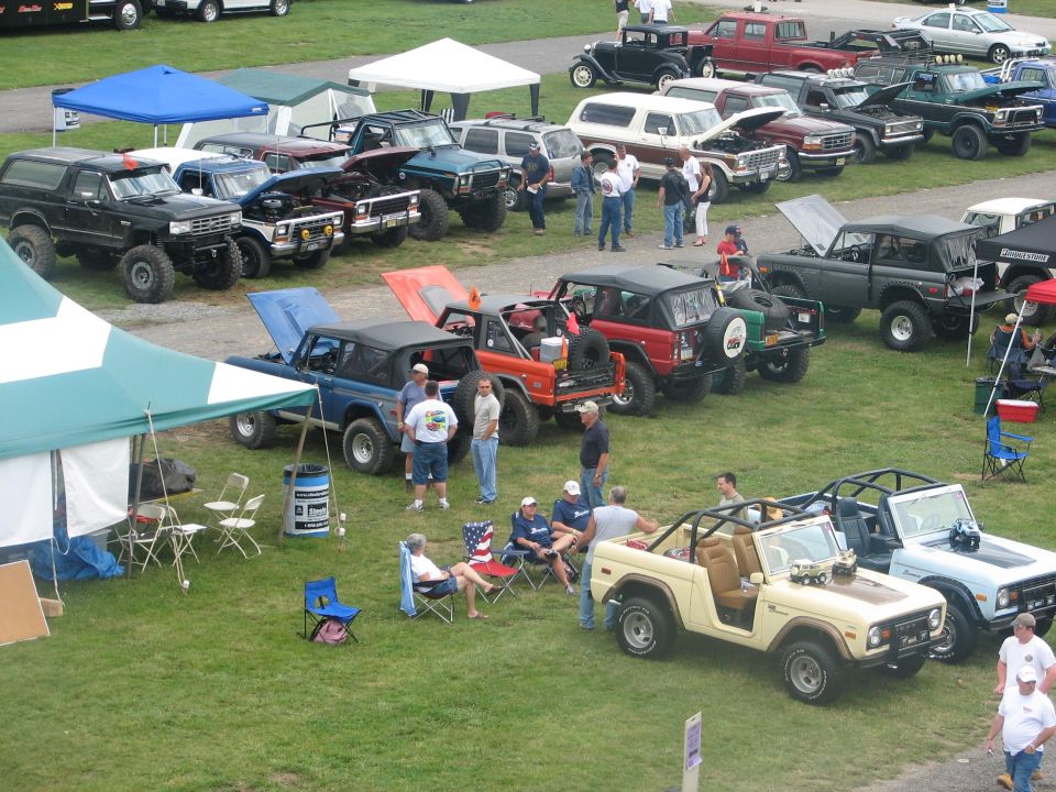 Aerial view of a Bronco club show field with early and full-size Ford Broncos and canopy tents