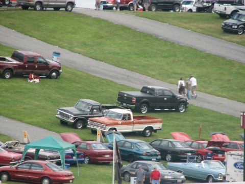 1992 Ford Bronco - An orange and white pickup truck is parked on a grassy field alongside other vehicles.