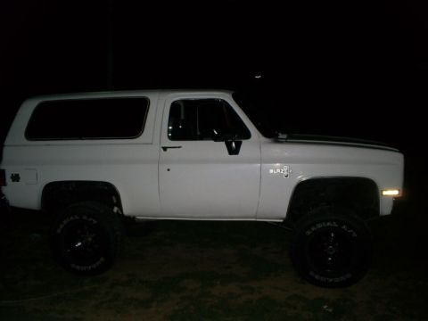 1991 Ford Bronco - This white Chevrolet K5 Blazer features a lifted suspension and black trim, photographed at night.