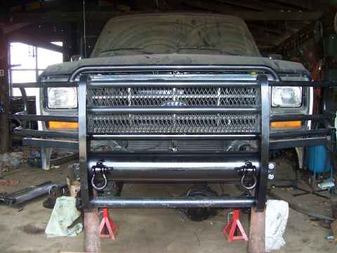 1983 Ford Bronco - A dusty Ford Bronco is parked in a garage, its front end equipped with a heavy-duty brush guard.