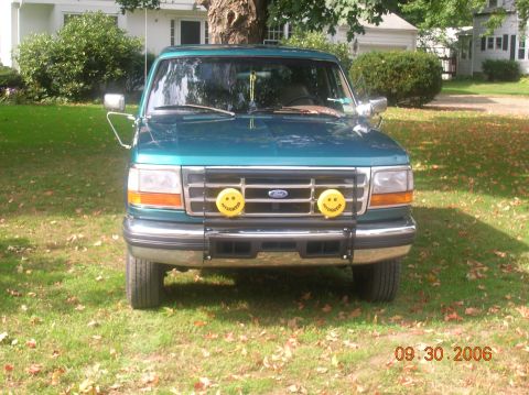1996 Ford Bronco - Teal Ford truck parked on grass with a bull bar and smiley face fog lights.