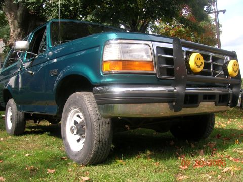 1996 Ford Bronco - 1996 Ford Bronco parked on grass with autumn leaves, a brush guard and smiley face lights.