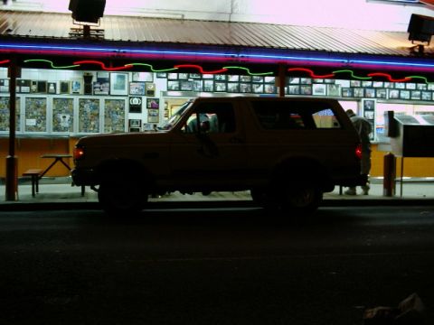 1988 Ford Bronco - A Ford Bronco is parked outside a brightly lit diner at night, with people visible inside.