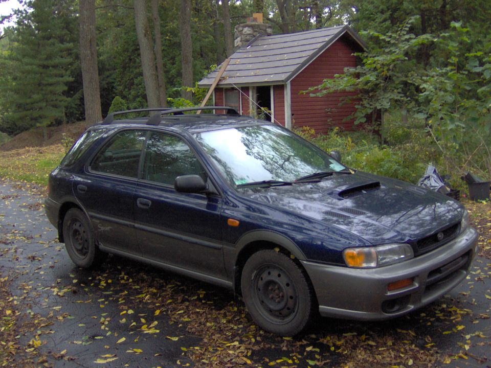 Dark blue Subaru Impreza wagon parked outdoors near a red shed
