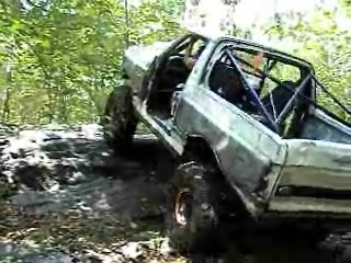 1995 Ford Bronco - This modified truck navigates a challenging rocky path in a wooded area.