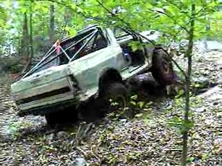 1995 Ford Bronco - This off-road vehicle navigates a challenging wooded terrain with a visible roll cage.