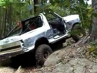 1995 Ford Bronco - This off-road vehicle navigates a rocky, wooded terrain, showing its modified roll cage and tires.