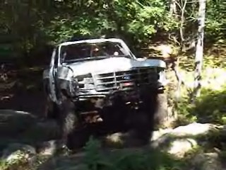 1995 Ford Bronco - 1995 Ford Bronco navigating a rocky path in a forest setting.