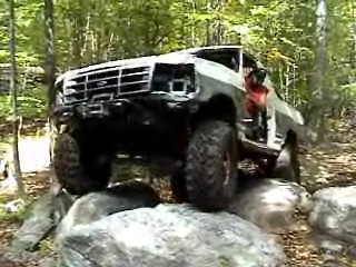 1995 Ford Bronco - A white Ford Bronco navigates a rocky trail in a wooded area.