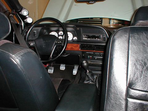 1993 Ford Thunderbird - The interior of a 1993 Ford Thunderbird features a wood-grain trim, aftermarket gauges, and a manual transmission shifter.