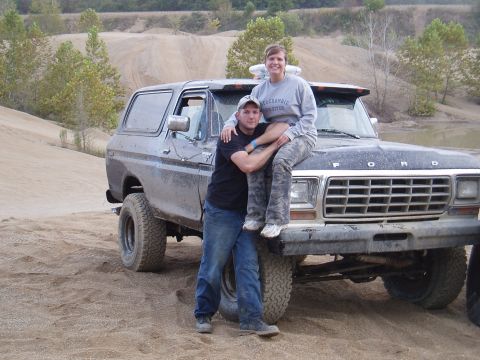 1979 Ford Bronco - A couple sits on the hood of a dirty Ford Bronco in an off-road park.