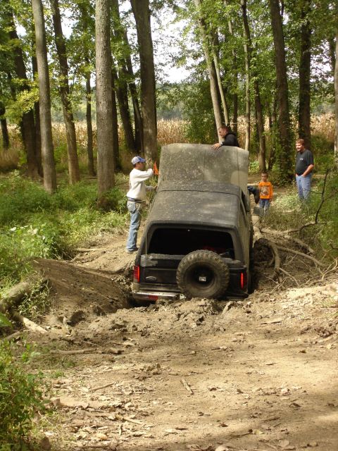 1979 Ford Bronco - A 1979 Ford Bronco is stuck in a muddy ditch while people watch.