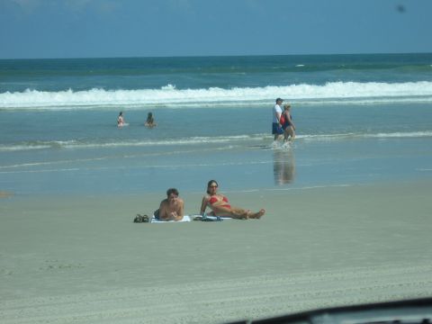 1974 Ford F-100 - People enjoy a sunny day at the beach with waves crashing on the shore.