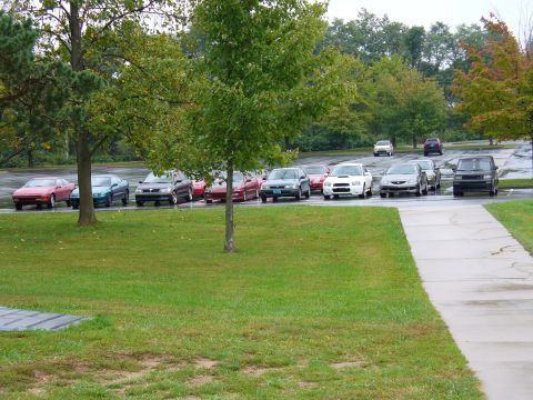 1991 Ford Probe - A variety of vehicles are parked in a lot on a cloudy day, with a white Subaru WRX being prominent.