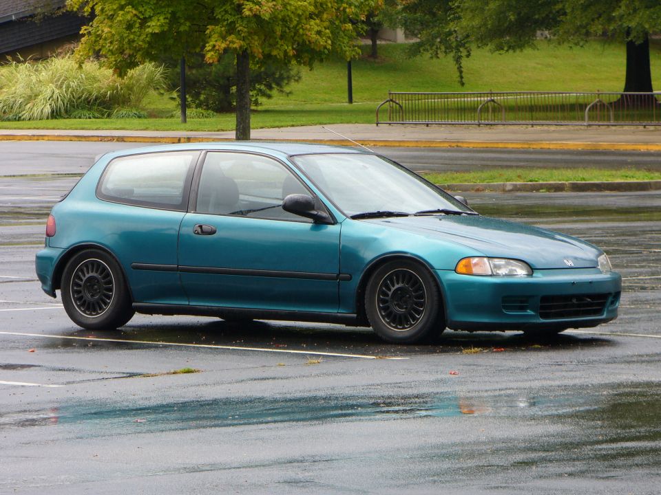 Teal 1990s Honda Civic hatchback parked on wet asphalt