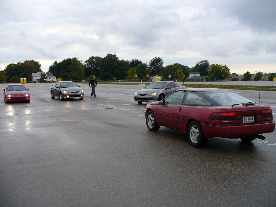 Red 1991 Ford Probe coupe from rear, license plate V404, on wet asphalt