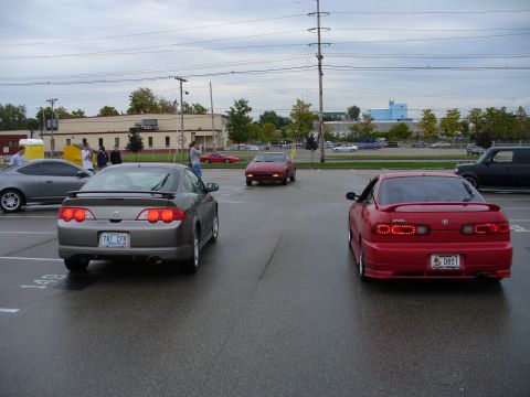 1991 Ford Probe - Two Acura Integra coupes are parked in a lot, with a third car driving away in the distance.