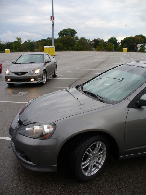 1991 Ford Probe - Two grey coupes are parked in an outdoor lot under a cloudy sky.
