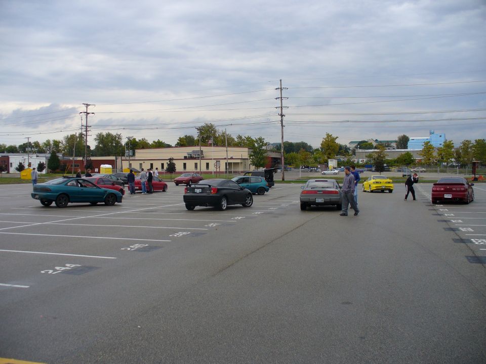 Teal coupe with a spoiler parked in a lot with other cars