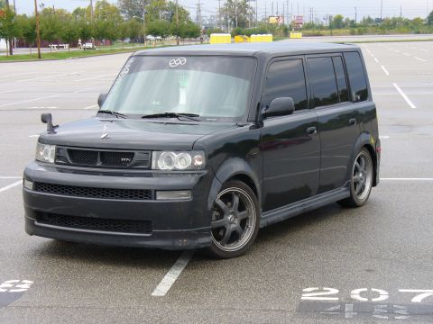 1991 Ford Probe - This dark-colored Scion xB is parked in an empty lot, showing its distinctive boxy shape and aftermarket wheels.