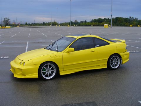 1991 Ford Probe - A yellow coupe sits in a wet parking lot under an overcast sky.
