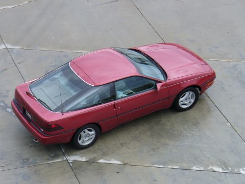 1991 Ford Probe - High overhead view of a red first-generation Ford Probe hatchback coupe parked on a concrete pad, showing the large glass hatch, factory al…