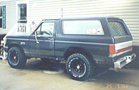 1989 Ford Bronco - Side view of a 1989 Ford Bronco with aftermarket wheels parked in front of a building.
