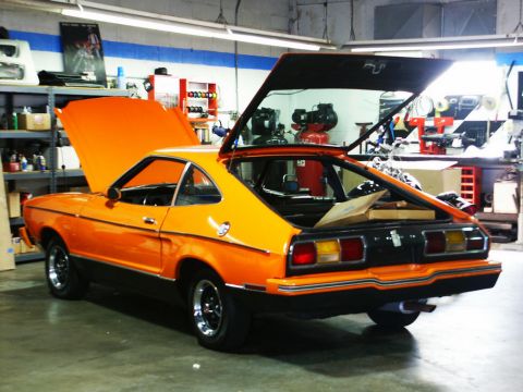 2001 Mercury Grand Marquis - An orange coupe sits in a garage with its hood and trunk open, revealing its interior and engine bay.