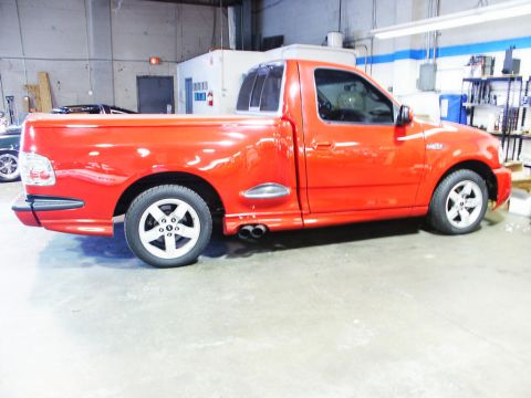2001 Mercury Grand Marquis - A red pickup truck is parked inside a garage with shelves in the background.