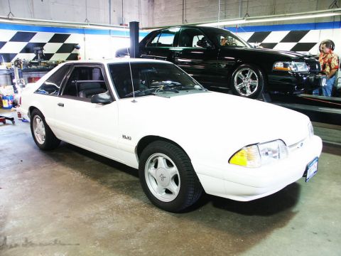 2001 Mercury Grand Marquis - A white coupe is parked in a garage, with a black sedan elevated behind it.