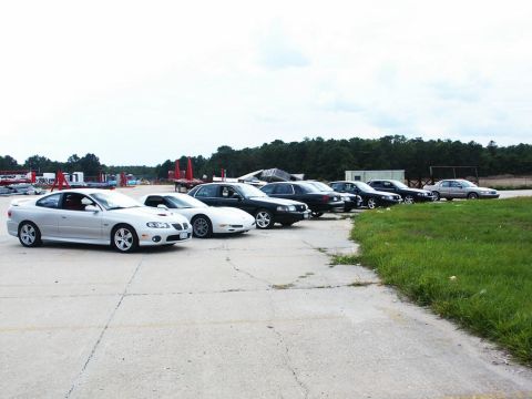 2001 Mercury Grand Marquis - A group of cars, including a silver coupe and several sedans, are parked outdoors on a cloudy day.