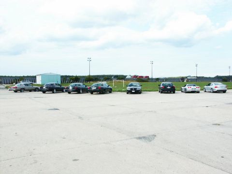 2001 Mercury Grand Marquis - A variety of vehicles are parked in an open lot under a cloudy sky.