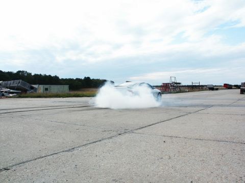 2001 Mercury Grand Marquis - A silver car performs a burnout on a concrete surface, creating a massive cloud of smoke.