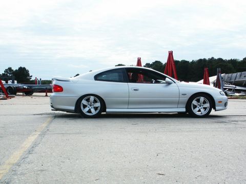 2001 Mercury Grand Marquis - A silver Pontiac GTO is seen from the side, parked outdoors with a trailer and red cones nearby.