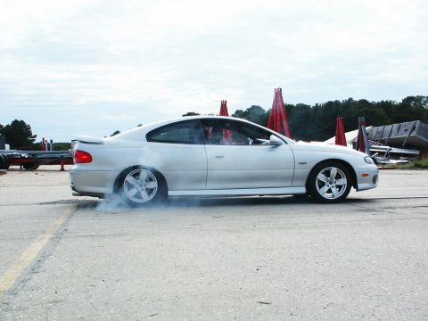 2001 Mercury Grand Marquis - A silver coupe performs a burnout, kicking up smoke as it spins its tires on the asphalt.
