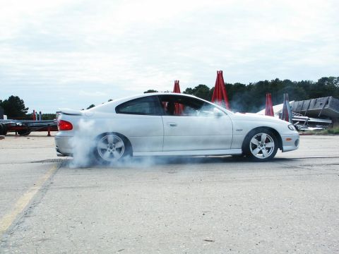 2001 Mercury Grand Marquis - White coupe performing a burnout with smoke billowing from the rear tires.
