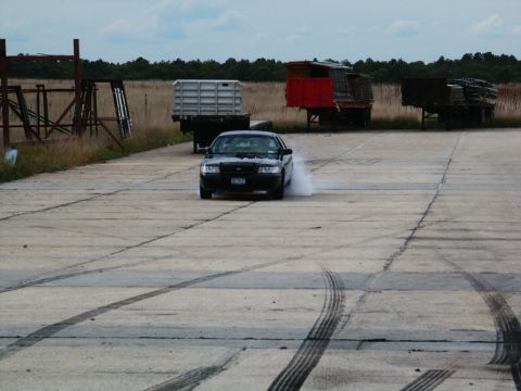 2001 Mercury Grand Marquis - A black 2001 Mercury Grand Marquis is seen performing a burnout on a concrete surface, leaving tire marks.