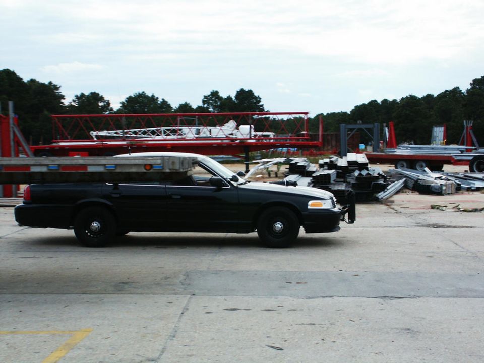 Black 2001 Mercury Grand Marquis sedan, side view, parked on concrete with construction equipment in background
