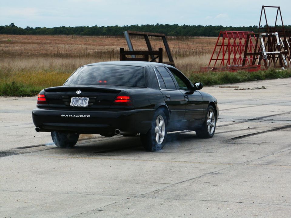 Black sedan doing a burnout, 'MARAUDER' text visible on trunk lid