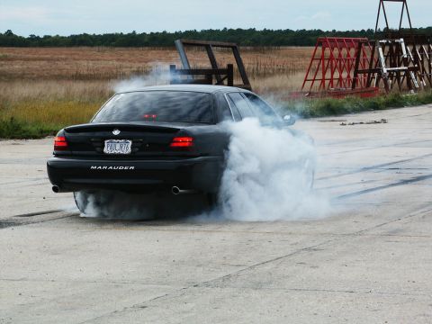 2001 Mercury Grand Marquis - A black sedan performs a burnout, emitting thick smoke from its tires.