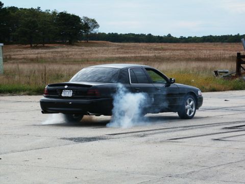 2001 Mercury Grand Marquis - A black 2001 Mercury Grand Marquis performs a burnout, kicking up a cloud of smoke.