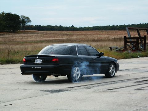 2001 Mercury Grand Marquis - Black Mercury Marauder performing a burnout on a paved surface with smoke billowing.