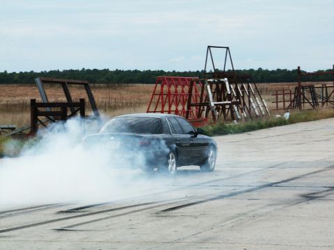 2001 Mercury Grand Marquis - A black sedan performs a burnout, kicking up a large cloud of smoke on a track.