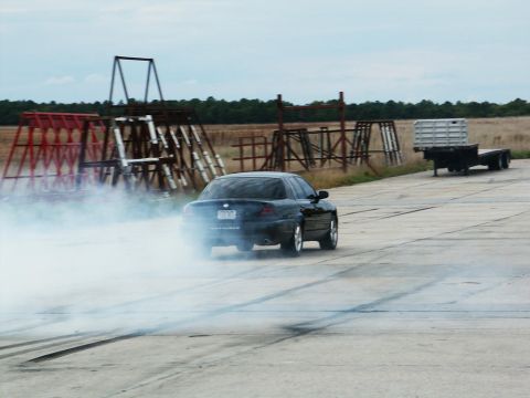 2001 Mercury Grand Marquis - Dark sedan performing a burnout, kicking up a lot of smoke.