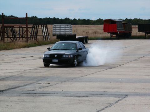 2001 Mercury Grand Marquis - A black Mercury Grand Marquis performs a burnout on a concrete surface, creating a large cloud of smoke.